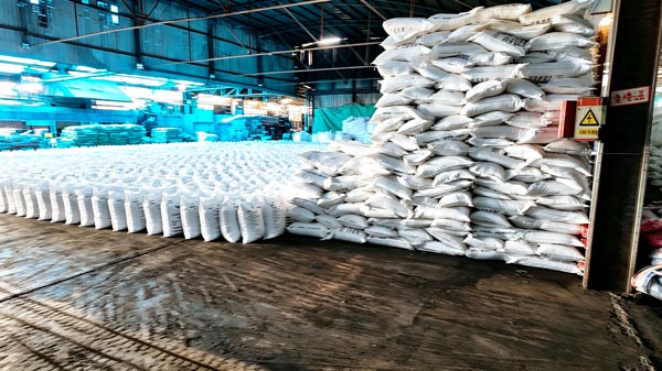 Symmetrical row alignment of palletized Aditya Birla caustic soda flakes stacked three levels high in storage bay