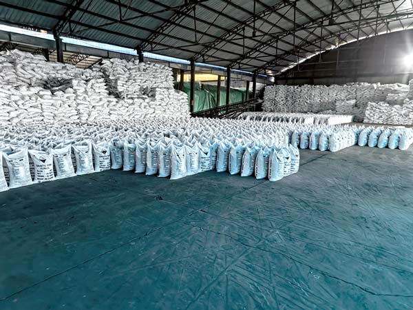 Neatly arranged high stack of 25kg caustic flakes bags inside packaging workshop floor