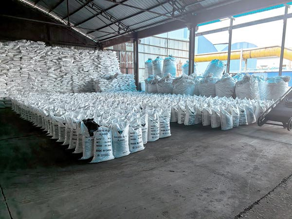 Warehouse loading bay door open with stacks of lye flakes pallets ready for truck loading