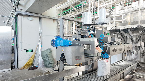 Industrial environment with automated conveyor and bagging equipment in a caustic pearl production facility