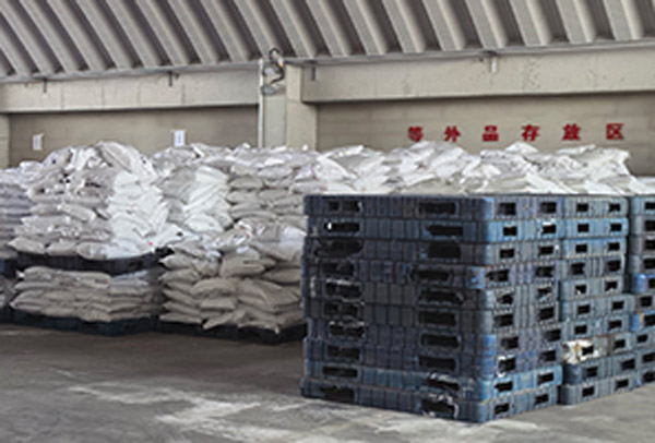 Symmetrical five bag layer configuration stacked on a plastic pallet inside a caustic soda flakes 99 warehouse