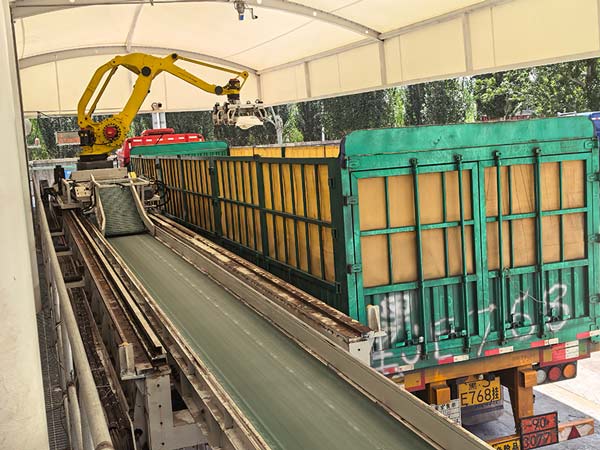 Forklift operator loading palletized 25kg caustic soda NaOH bags onto a heavy transport trailer