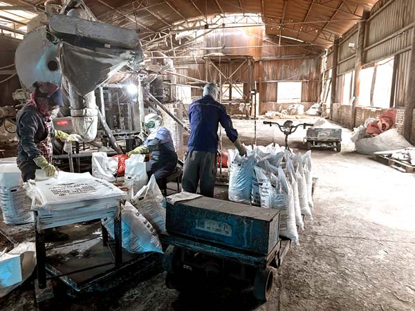 Factory technician monitoring automated temperature controls on caustic soda pearls processing line