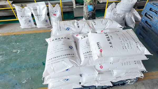 Stacked 25kg caustic soda flake bags in factory warehouse with low bulk unit price