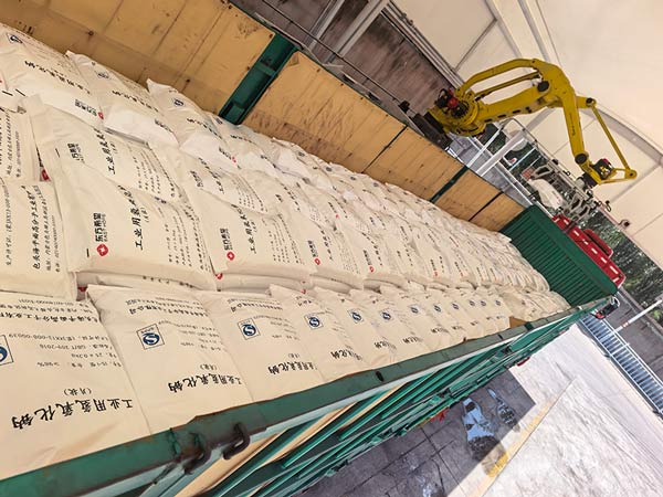Forklift loading pallets of 25kg sodium hydroxide flake bags for export shipping