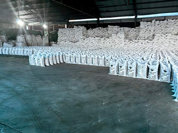 Palletized cargo of sealed 25kg sodium hydroxide flakes bags waiting in climate controlled warehouse