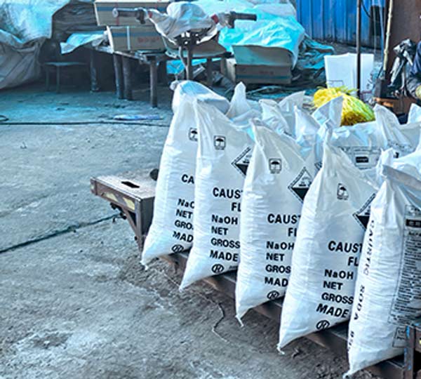 Overlapping cross-tie stacking arrangement of 25kg lye flakes for soap making packages inside dry storage depot
