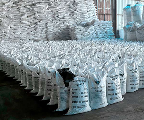 Macro view of multi language product warnings and GHS corrosive pictograms printed on an Aditya Birla caustic soda flakes sack