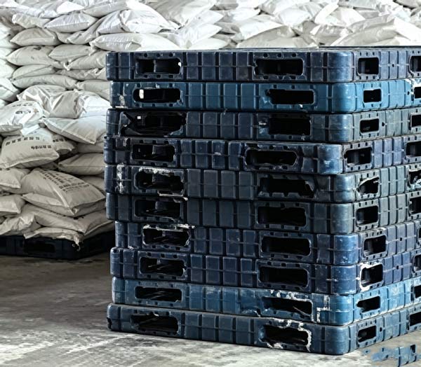 Pallet position identification tag fixed to the front edge of a loaded Grasim caustic soda flakes stack inside logistics center