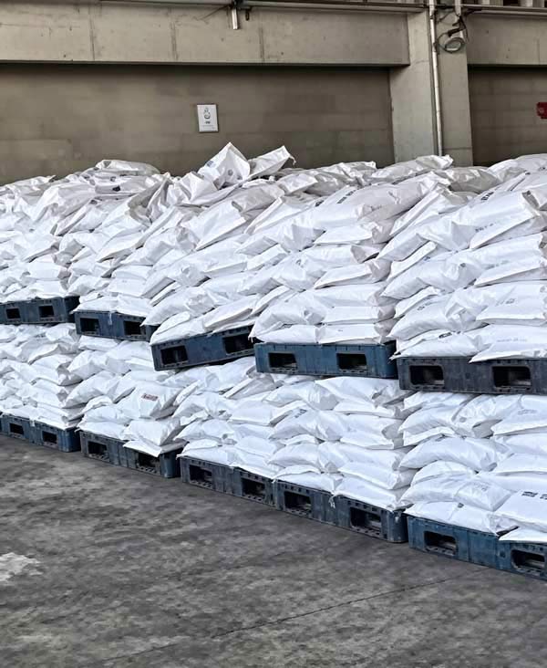 Hash-pattern interlocking tie arrangement holding 25kg Grasim caustic soda flakes bags stable on a heavy duty plastic pallet