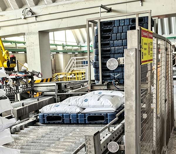 Parallel dual-band buckle strapping tensioning four sides of a multi-tier block stack of bagged NaOH flakes inventory