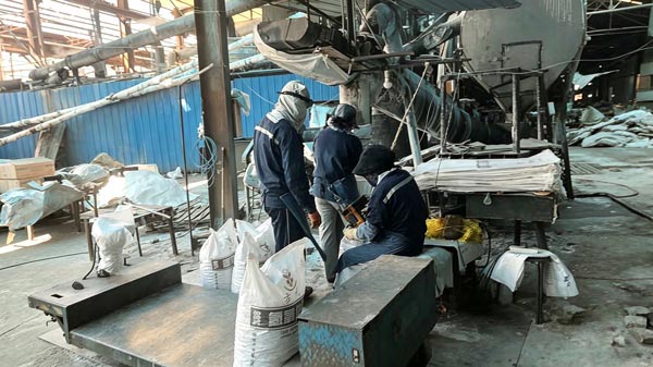 Factory worker using a handheld heat sealer to double seal the inner PE liner of a 25 kg caustic soda online bag