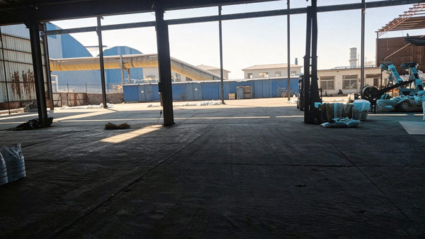 Overhead monorail crane hoisting heavy chemical bag pallets inside a 50kg caustic soda factory warehouse bay
