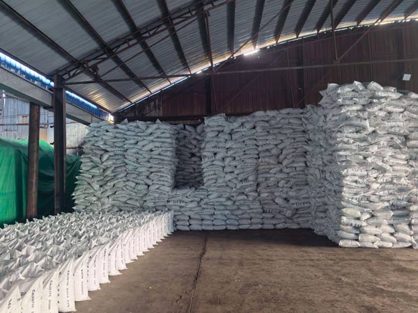Spacious factory warehouse stacked with large quantities of white 25kg caustic soda pure bags