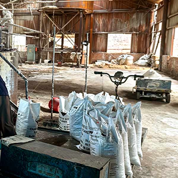 Floor rail system anti-settling ground storage zone holding massive caustic soda bag inventory inside supplier factory