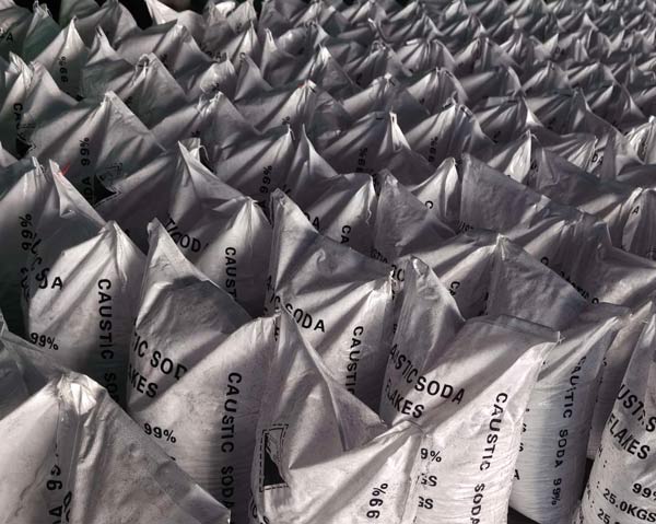 Top angle view of tightly packed White Tulip caustic soda bags showing 99 percent purity label in warehouse.