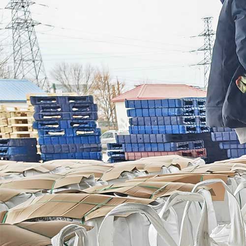 Outdoor chemical storage yard featuring palletized 99 sodium hydroxide bulk bags prepared for international ocean freight.