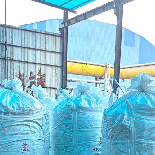 Bulk jumbo bags of cosmetic-grade sodium hydroxide used in hair products and personal care manufacturing, staged outside a chemical facility.