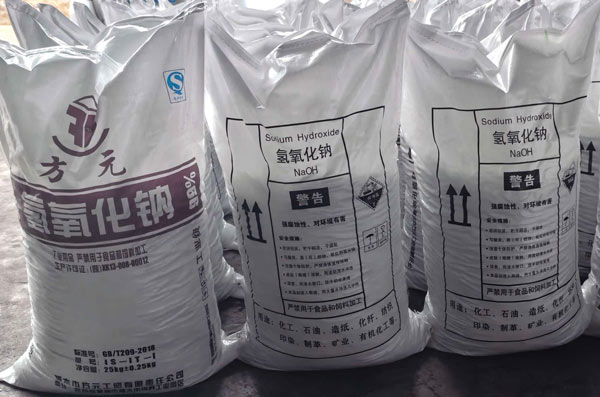 Front view of 25kg sodium hydroxide soda bags showing clear NaOH labels and industrial safety warning symbols.