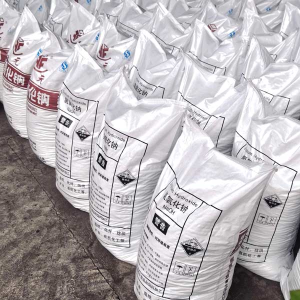 Arrayed bags of industrial sodium hydroxide soda lined up on factory floor for bulk export palletizing.