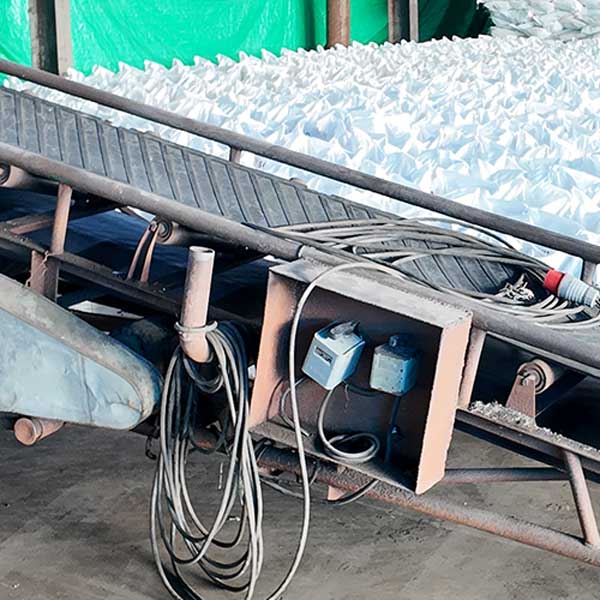 Chemical manufacturing facility conveyor belt line delivering high-purity NaOH for metallurgy applications.