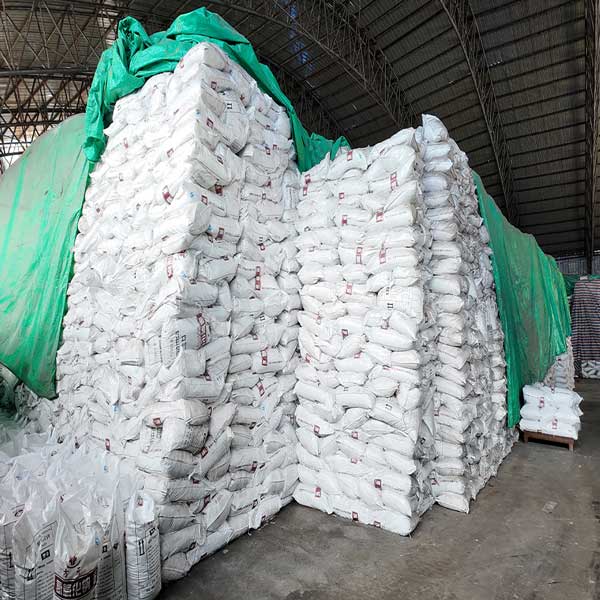 Massive warehouse stacks of bagged solid Sodium Hydroxide NaOH in 25kg bags ready for wholesale delivery.