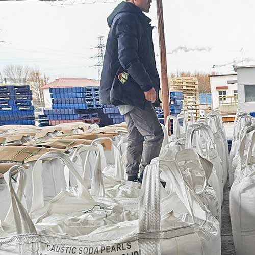 Close-up of the legible 'CAUSTIC SODA PEARLS' text printed on heavy-duty white bulk bags, which are factor-direct with a competitive price of sodium hydroxide per ton.