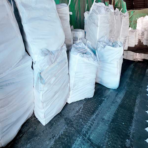 Bulk white FIBC jumbo bags filled with caustic soda stored in a chemical warehouse by a reliable sodium hydroxide supplier.