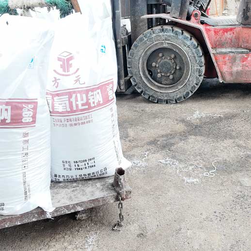 Close-up view of white bags clearly printed with 99% purity specifications for 25kg sodium hydroxide.