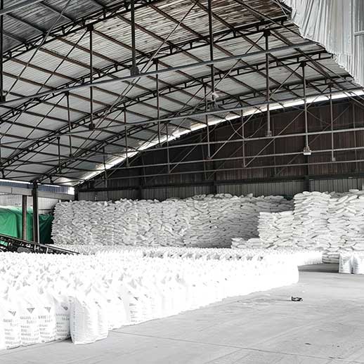 Heavy material handling setup showing packaged 25kg sodium hydroxide bags next to warehouse transport machinery.
