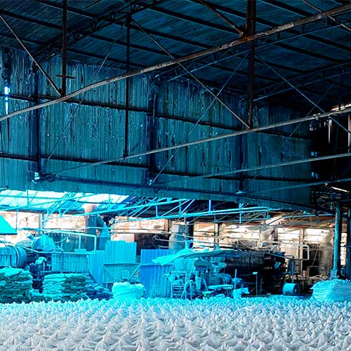Massive warehouse inventory of 25kg caustic soda bags organized to guarantee a factory-direct, stable sodium hydroxide flakes price.