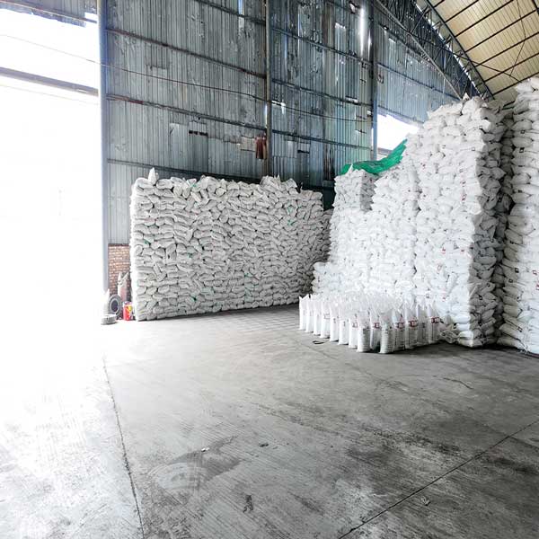Foreground view of printed 25kg caustic soda bags organized in a factory warehouse operated by top sodium hydroxide manufacturers.