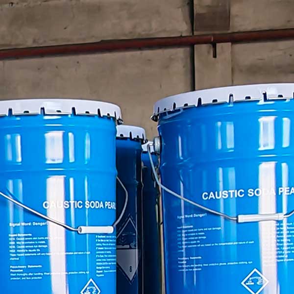 Securely stacked blue chemical drums prepared for maritime cargo shipping and global distribution of caustic beads.