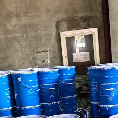 Industrial blue metal pails stacked on wooden pallets, ideal for bulk caustic soda beads for sale.