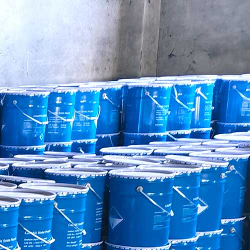 Warehouse inventory of stacked blue steel drums ready for local regional dispatch from caustic soda beads suppliers near me.