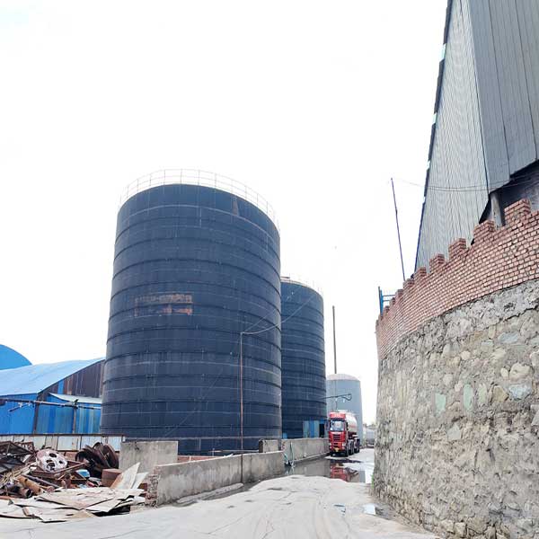 Massive industrial storage tanks containing bulk liquid 50 caustic soda at a chemical factory.