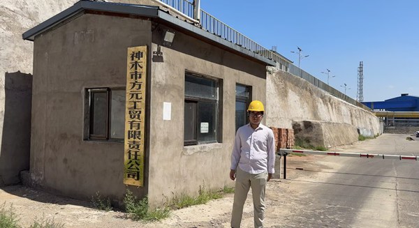 Site manager standing near corporate entrance gate of certified caustic soda 98 manufacturing plant.