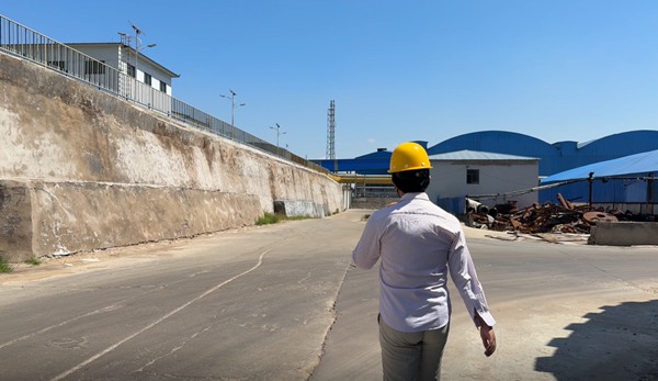 Industrial safety inspector in hardhat surveying manufacturing facilities for caustic soda 98 bulk output.