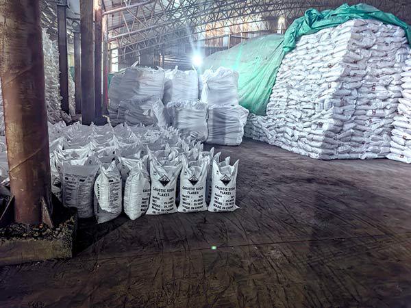 Protective green tarp tarpaulins covering massive chemical stockpiles for clients who buy caustic in bulk.