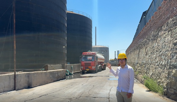 Technical manager explaining raw material transport logistics in front of heavy tanker truck for soda caustic flake production.